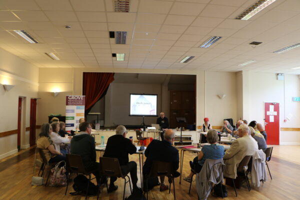 groups of people sat at tables listening to a speaker in a church hall